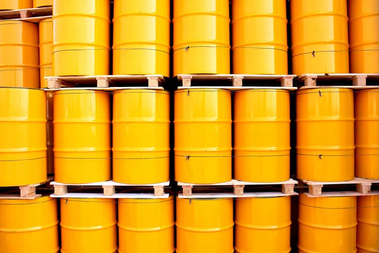 Yellow oil drums on an industrial transport site stacked om palettes.